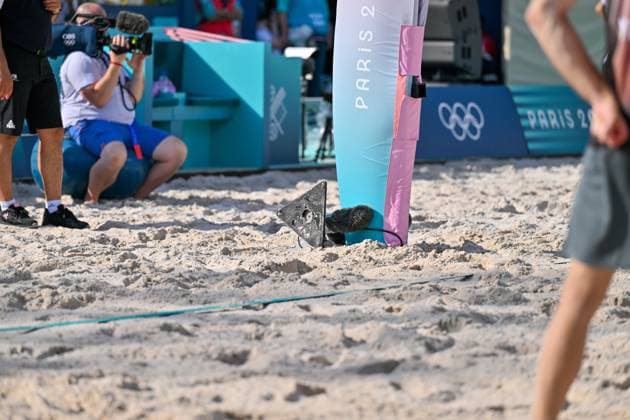 Olympische Spiele Beach volleyball, Beachvolleyball ; Paris 01.08.2024 Vorrunde, Herren, GER_AUS, Clemens Wickler stolpert über Mikrofon, das am Netzpfosten aufgestellt ist, zum Spielfeld hin. Anschließend reisst Wickler es aus dem Sand und wirft es nach hinten. Copyright: xBEAUTIFULxSPORTS TomxBlochx