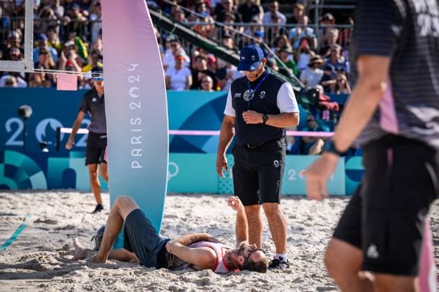 01.08.2024, Paris, Stadion Eiffelturm Beachvolleyball, Olympische Spiele, Vorrunde Clemens Wickler (GER) stolpert über Netzkamera und verletzt sich Schiedsrichter Schiri Giovanni Bake (RSA) bei ihm