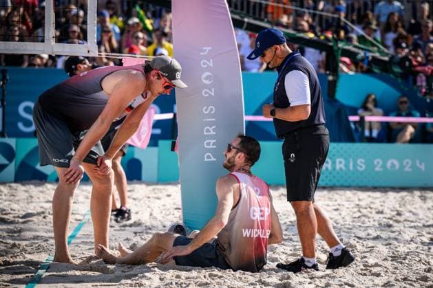 01.08.2024, Paris, Stadion Eiffelturm Beachvolleyball, Olympische Spiele, Vorrunde Clemens Wickler (GER) stolpert über Netzkamera und verletzt sich Nils Ehlers (GER) und Schiedsrichter Schiri Giovanni Bake (RSA) bei ihm