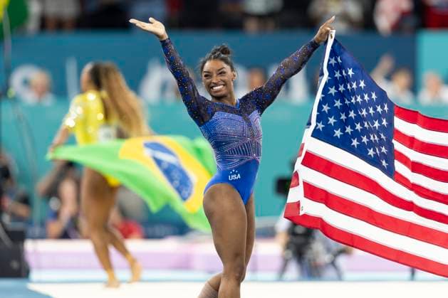 Sport Themen der Woche KW31 Sport Bilder des Tages BILES Simone (USA, mi., Gold) freut sich ueber ihren Sieg, im Hintergrund die Gewinnerin der Silbermedaille ANDRADE Rebeca (BRA), Freude, Lachen, mit Flagge; Turnen Geraeteturnen Frauen Mehrkampf, Finale, am 01.08.2024, Olympische Spiele Paris 2024 Frankreich; Â *** BILES Simone USA, mi , gold is happy about her victory, in the background the winner of the silver medal ANDRADE Rebeca BRA , joy, laughter, with flag Gymnastics apparatus gymnastics women all-around, final, on 01 08 2024, Olympic Games Paris 2024 France Â