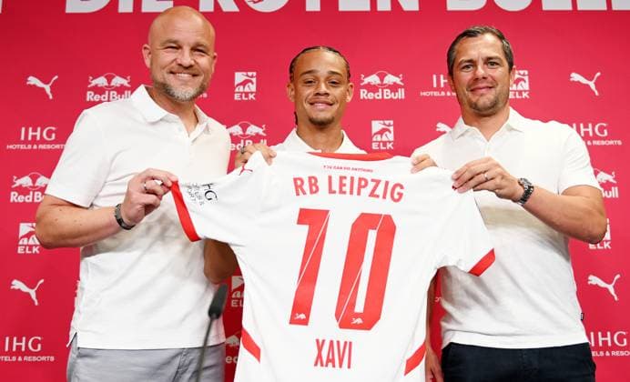 Fußball-Bundesliga Saison 2024 2025, Pressekonferenz mit Xavi Simons (Offensives Mittelfeld RB Leipzig, Rueckennummer 10), Marcel Schäfer (Geschäftsführer RB Leipzig) und Rouven Schröder (Sportdirektor RB Leipzig) (06.08.2024). Rouven Schröder (Sportdirektor RB Leipzig), Xavi Simons (Offensives Mittelfeld RB Leipzig, Rueckennummer 10) und Marcel Schäfer (Geschäftsführer Sport RB Leipzig) (v.l.n.r.) bei der Pressekonferenz von RB Leipzig (06.08.2024). Auf der PK wird die Verlängerung der Leihe von Xavi (von Paris Saint-Germain) bekanntgegeben. Schröder, Xavi und Schäfer halten ein Trikot von Xavi mit der Nummer 10 in die Höhe. Leipzig Sachsen Deutschland Red-Bull-Trainingsgelände am Cottaweg