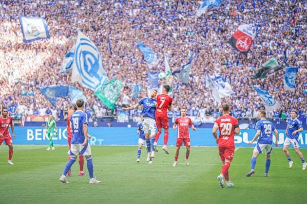 Fußball: 2. Bundesliga Saison 2024 - 2025, 4. Spieltag - FC Schalke 04 vs. 1. FC Köln - Veltins-Arena, Gelsenkirchen: Kopfball-Szene zwischen Schalkes Janik Bachmann und Kölns Dejan Ljubicic vor der Schalker Fantribüne