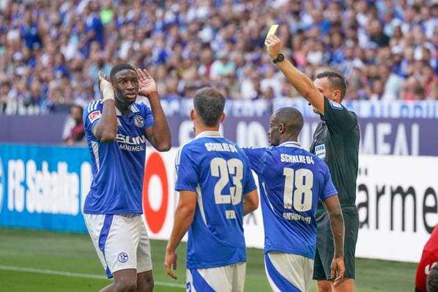 Fußball: 2. Bundesliga Saison 2024 - 2025, 4. Spieltag - FC Schalke 04 vs. 1. FC Köln - Veltins-Arena, Gelsenkirchen: Schalkes Ibrahima CissÃ Cisse bekommt von Schiedsrichter Sven Jablonski die Gelbe Karte