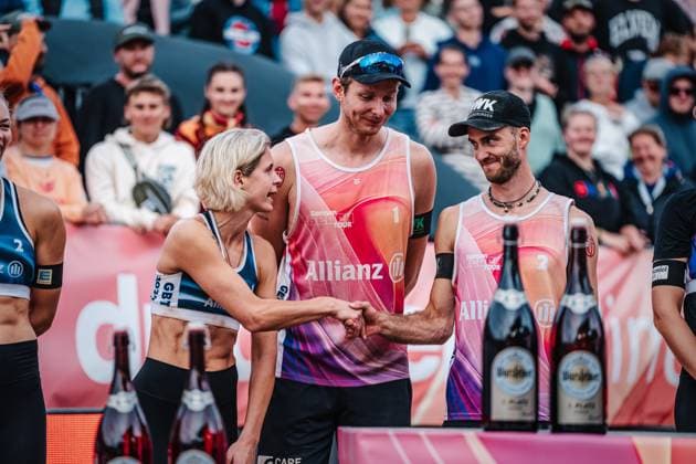 Beachvolleyball Frauen und Männer Allianz German Beach Tour Deutsche Beachvolleyball-Meisterschaft 2024 01.09.2024 links Laura Ludwig und rechts Clemens Wickler geben sich die Hand, in der Mitte Nils Ehlers Timmendorfer Strand Ahmann-Hager-Arena Schleswig-Holstein Deutschland