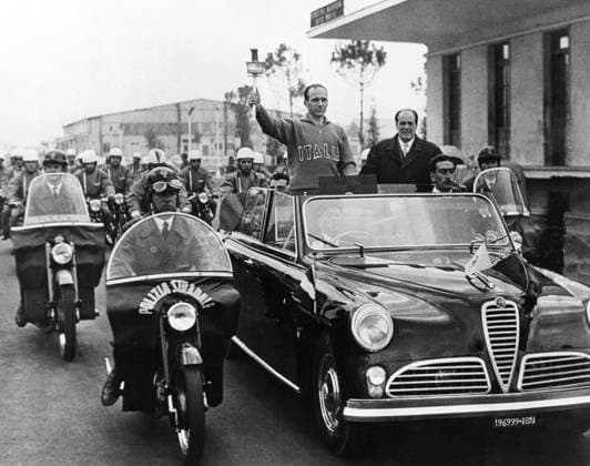 ITALY ROME 1956-01-24. Giuseppe Dordoni, Italian track and field athlete, carries the Olympic torch as it arrives by car with motorcycle escort at Ciampino airport in Rome en route to Cortina in connection with the 1956 Winter Olympics. Rom Italy OS sp_sw x5600x *** ITALY ROME 1956 01 24 Giuseppe Dordoni, Italian track and field athlete, carries the Olympic torch as it arrives by car with motorcycle escort at Ciampino airport in Rome en route to Cortina in connection with the 1956 Winter Olympics Rome Italy OS sp sw x5600x  Copyright: xPaulxPopper SVTx 1956 WINTER OLYMPICS