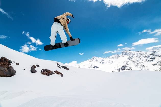 snowboarder jumps from a big air with a board grab, a nose or tail trick in rotation, against the backdrop of snow-capped mountains and the bright sun a snowboarder jumps from a big air with a board grab, a nose or tail trick in rotation, against the backdrop of snow-capped mountains and the bright sun. (License=RF) 22194662 ,model released, Symbolfoto Copyright: xZoonar.com IanxIankovskiix 22194662 ,model released, Symbolfoto ,property released