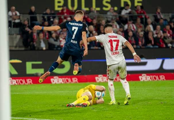 Jonas Urbig (1. FC Koeln, 40) hält den Ball fest. Filip Bilbija (SC Paderborn, 7) springt über den Torwart. Leart Paqarada (1. FC Koeln, 17) steht rechts daneben. 1. FC Köln - SC Paderborn, 25.10.2024, Fussball, 2. Bundesliga, RheinEnergieStadion Köln