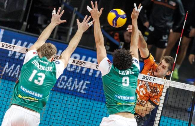 16.11.2024, Berlin, Volleyball: 1.Bundesliga, Maenner, 8. Spieltag, BR Volleys - TSV Haching Muenchen, Max-Schmeling-Halle. Berlins Moritz Reichert (r-l) spielt den Ball gegen den Block aus AJ Lewis und Mark Gumenjuk von TSV Haching Muenchen. BR Volleys - TSV Haching Muenchen