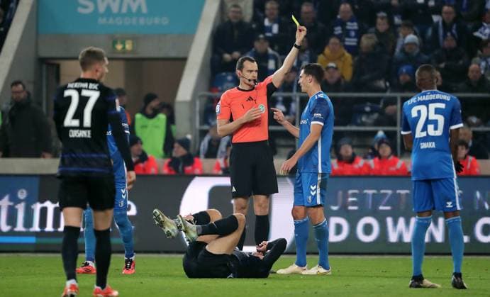Schiedsrichter Richard Hempel gelbe Karte für Tobias Müller nach Foulspiel an Derry Scherhant Fußball Fussball 2.Bundesliga Herren 14. Spieltag Saison 2024 2025 29.11.2024 1.FC Magdeburg FCM vs. Hertha BSC Berlin DFL regulations prohibit any use of photographs as image sequences and or quasi-video.