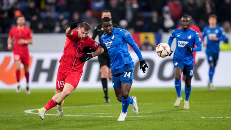 v.li.: Daniel Popa (FCSB Bukarest, 19), Stanley Pierre Nsoki (N Soki, Hoffenheim, 34), Zweikampf, Spielszene, Duell, duel, tackle, tackling, Dynamik, Action, Aktion, 12.12.2024, Sinsheim (Deutschland), Fussball, UEFA Europa League, Gruppenphase, TSG 1899 Hoffenheim - FCSB Bukarest, 12.12.2024, Sinsheim (Deutschland), Fussball, UEFA Europa League, Gruppenphase, TSG 1899 Hoffenheim - FCSB Bukarest, DFB DFL REGULATIONS PROHIBIT ANY USE OF PHOTOGRAPHS AS IMAGE SEQUENCES AND OR QUASI-VIDEO.