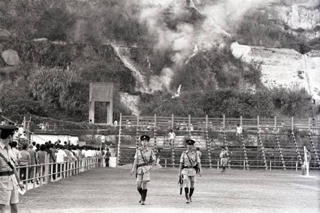 Flames and smoke rise from a scrub fire on the hillside overlooking the Boundary Street Stadium, where a heart-stopping soccer match betwen Yuen Long and Tung Sing is being held. Pictured here are policemen at the site to see if it is necessary to evacuate the spectators in the stadium. 25APR77 Hong Kong Hong Kong EDITORIAL USE ONLY  Copyright: xx MER2016080116152506 RobinxLamxKitx 0795656516st