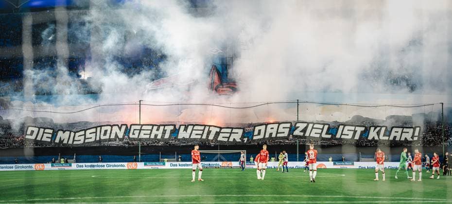 Fußball Männer Saison 2024 2025 2. Fußball-Bundesliga 23. Spieltag Hamburger SV vs. 1. FC Kaiserslautern 21.02.2025 Choreo der HSV Nordtribüne Fans Die Mission Geht Weiter Das Ziel Ist Klar mit Pyrotechnik zusammengefügtes Panorama Hamburg Volksparkstadion Hamburg Deutschland
