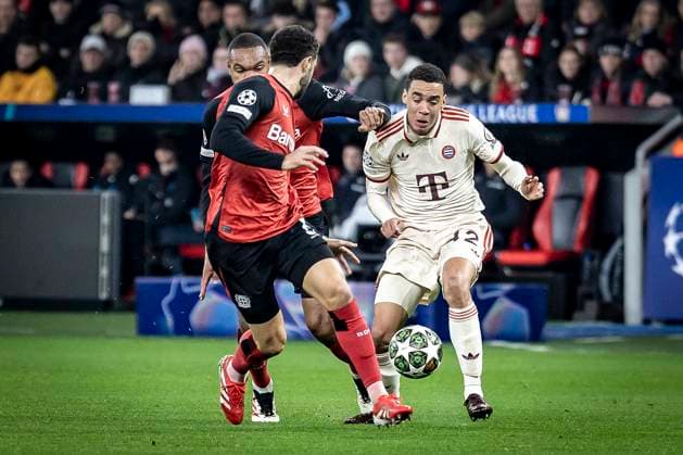 UEFA Champions League, Bayer 04 Leverkusen - FC Bayern München; 11.03.2025 Jamal Musiala (FC Bayern München, 42) wird von Jonathan Tah (Bayer 04 Leverkusen, 4) und Mario Hermoso (Bayer 04 Leverkusen) bedrängt; UEFA Champions League, Bayer 04 Leverkusen - FC Bayern München, Achtelfinale, Rückspiel, 11.03.2025 in der BayArena in Leverkusen. Copyright: xBEAUTIFULxSPORTS AxelxKohringx