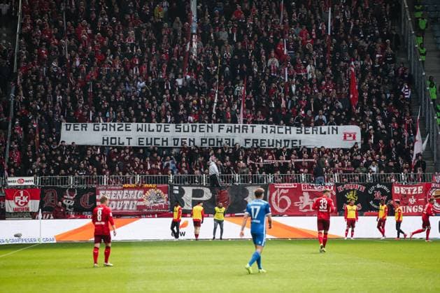 Die Fans vom 1. FC Kaiserslautern halten ein Banner hoch mit der Aufschrift Der ganze wilde Südenfährt nach Berlin, holt euch den Pokal Freunde! - 2. Fußball Bundesliga Saison 2024-2025 1. FC Magdeburg vs. 1. FC Kaiserslautern in der Avnet Arena in Magdeburg - Aktion,Fußball,Mann,Männer,Deutschland,06.04.2025