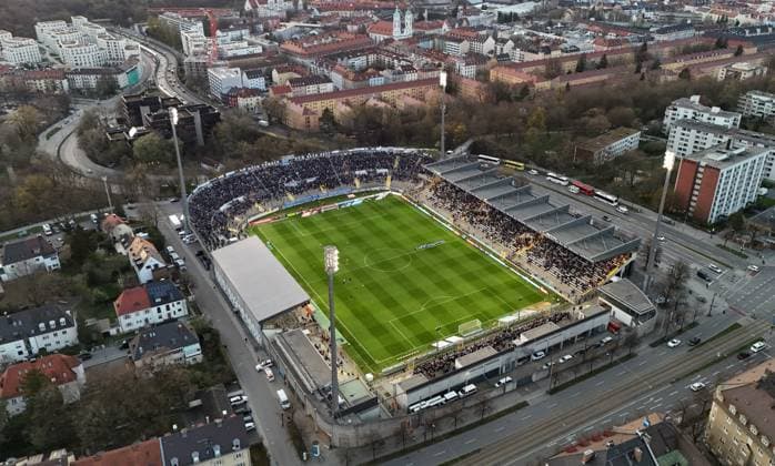Hier der Blick auf das Städtische Stadion an der Grünwalder Strasse, Grünwalder Stadion in München Giesing, Spielstätte u.a. des TSV 1860 München, FC Bayern München Amateure, mit Zuschauern, Fans bei Sonnenuntergang, Dämmerung, Flutlicht *** Here is the view of the municipal stadium on Grünwalder Strasse, Grünwalder Stadion in Munich Giesing, venue of TSV 1860 Munich, FC Bayern Munich Amateure, with spectators, fans at sunset, dusk, floodlights