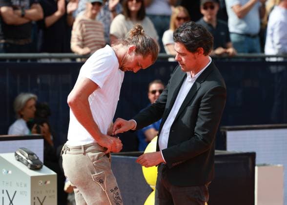 MTTC Iphitos Vorsitzender Dr. Fabian Tross schaut wie Sieger Alexander Zverev die Lederhose anzieht, Siegerehrung, Presentation Copyright: xJuergenxHasenkopfx