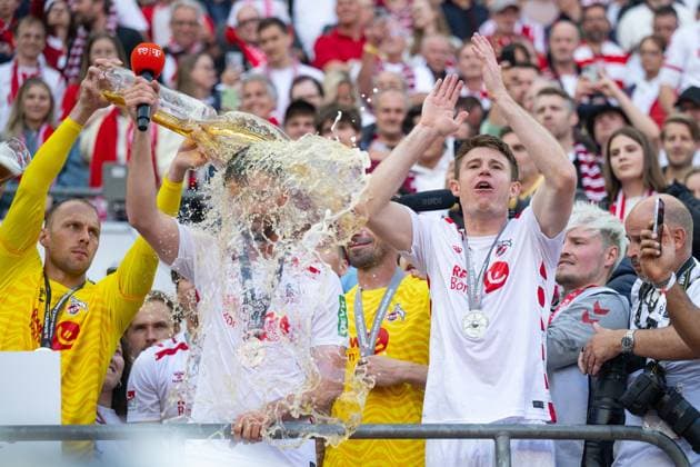 18.05.2025, Fussball, 2. Bundesliga, 34. Spieltag Saison 2024 2025, 1. FC Köln - 1. FC Kaiserslautern, Torwart Marvin Schwäbe (1. FC Köln) gibt Mark Uth (1. FC Köln) (m) eine Bierdursche, Dominique Heintz (1. FC Köln) (r) xRHR-FOTO TKx