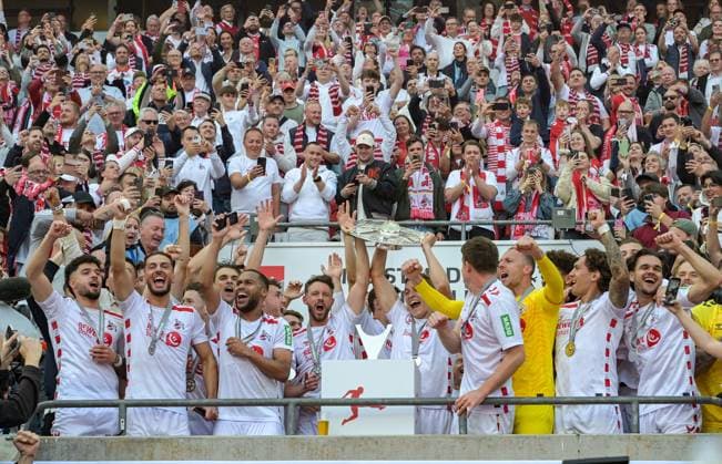 18.05.2025, xjpx, Fussball 2.Bundesliga, 1.FC Koeln - 1.FC Kaiserslautern v.l. Meister der 2. Bundesliga - 1. FC Koeln Die Mannschaft feiert mit der Schale, die von Mark Uth (Koeln -links) und Kapitän Timo Hübers (Koeln - rechts) präsentiert wird (DFL DFB REGULATIONS PROHIBIT ANY USE OF PHOTOGRAPHS as IMAGE SEQUENCES and or QUASI-VIDEO) Koeln