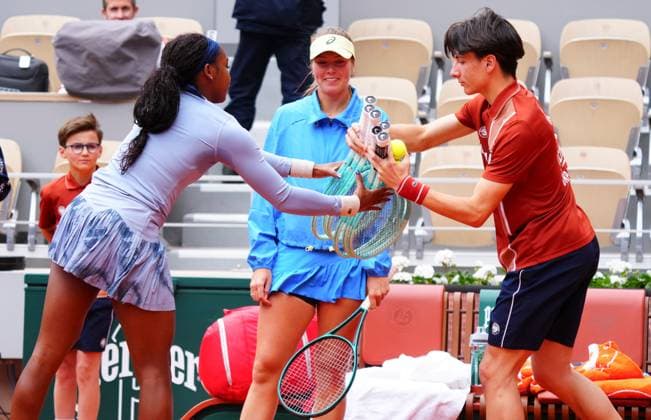 A ballboy delivers racquets to Coco Gauff after she walked onto court with an empty racquet bag as her opponent Olivia Gadecki looks on grinning French Open Tennis, Day Three, Tennis, Roland Garros, Paris, France - 27 May 2025 EDITORIAL USE ONLY No use with unauthorised audio, video, data, fixture lists, club league logos or live services. Online in-match use limited to 120 images, no video emulation. No use in betting, games or single club league player publications. Copyright: xJavierxGarcia Shutterstockx 15314625aq