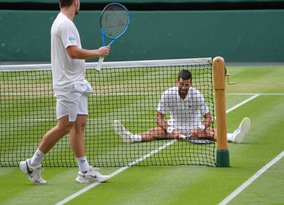 Tennis - 2025 Wimbledon Championships - Men™s singles - 3rd round - Miomir Kecmanovic v Novak Djokovic All England Lawn Tennis & Croquet Club - Friday 5th July 2025 Novak Djokovic jokes with Kecmanovic after stretching to win a thrilling point 