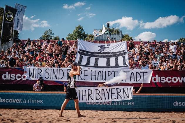Sport Bilder des Tages Beachvolleyball Männer Allianz German Beach Tour 2025 Tourstop München 13.07.2025 Paul Henning läuft ein in das Stadion während die Fangruppe Fraktion Bräune eine Choreo mit Pyrotechnik zeigt. Wir sind eure Hauptstadt ihr Bayern München Zentraler Hochschulsport Münche Bayern Deutschland