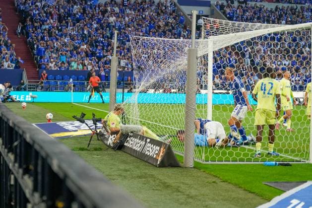 Deutschland: Fussball 2. Bundesliga 2025 26, 11. Spieltag - FC Schalke 04 vs Hertha BSC - VELTINS Arena Gelsenkirchen: Spieler von Hertha BSC landet nach einem Zweikampf im Tornetz, Kameras am Boden, dramatische Szene im Strafraum, hart umkämpftes Spiel, Ruhrpott-Fußballintensität.