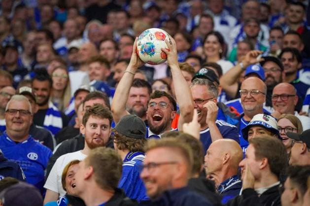 Deutschland: Fussball 2. Bundesliga 2025 26, 1. Spieltag - FC Schalke 04 vs Hertha BSC - VELTINS Arena Gelsenkirchen: Schalke-Fan jubelt mit gefangenem Spielball, ausgelassene Stimmung auf den Rängen, emotionale Fankultur, Ruhrpott-Fußball, enge Verbindung zwischen Fans und Spielgeschehen.