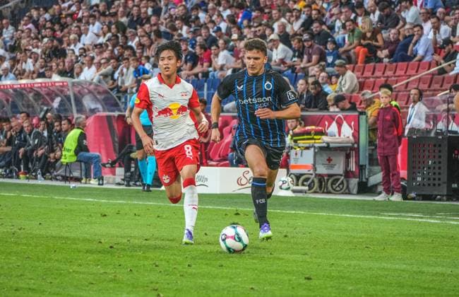 Fussball Österreich, UEFA Champions League 2025 2026, 3. Qualifikationsrunde - FC Red Bull Salzburg vs. Club Brügge - Red Bull Arena (Salzburg, Wals-Siezenheim, Österreich): Christos Tzolis (Club Brugge KV) mit Sota Kitano (Red Bull Salzburg) Copyright: xLukasxBierederx