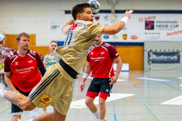 Renars Uscins (TSV Hannover-Burgdorf, Nr. 10) (v.l.), TSV Hannover-Burgdorf (beige) gegen Aalborg Handbold (rot) am 1. Spieltag des Internationalem Heide-Cups (08.08.2025,(Schneverdingen, GER), Copyright: xJanxGuentherx xTSVxHannover-Burgdorfx
