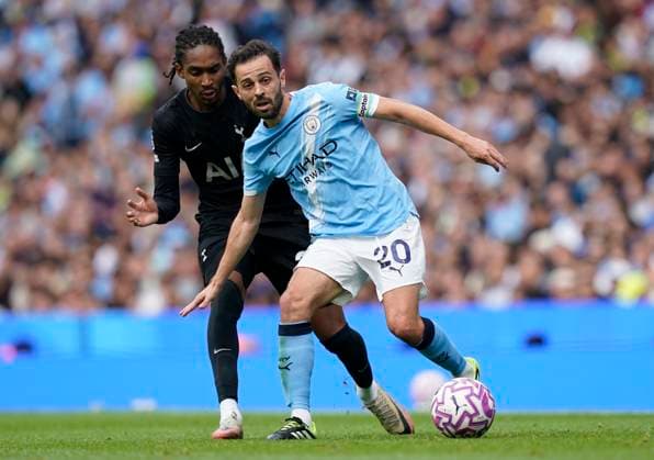 Manchester, England, 23rd August 2025. Bernardo Silva of Manchester City (R) is challenged by Djed Spence of Tottenham during the Manchester City vs Tottenham Hotspur Premier League match at the Etihad Stadium, Manchester. Picture credit should read: Andrew Yates Sportimage EDITORIAL USE ONLY. No use with unauthorised audio, video, data, fixture lists, club league logos or live services. Online in-match use limited to 120 images, no video emulation. No use in betting, games or single club league player publications. SPI_023_AY_MAN_CITY_SPURS SPI-4081-0023