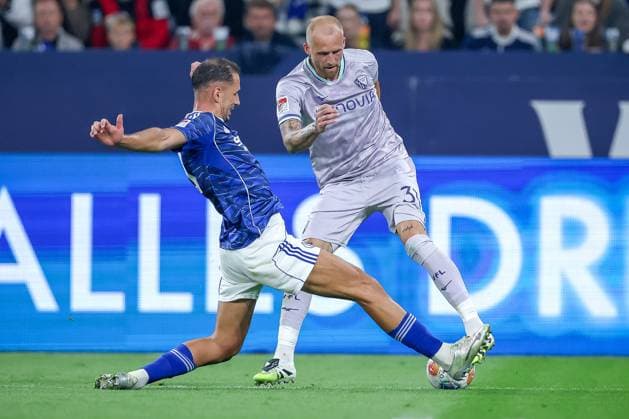 23.08.2025, Fußball, FC Schalke 04 - VfL Bochum, 3.Spieltag, 2. Fußball Bundesliga, Veltins-Arena Gelsenkirchen, Saison 2025 2026: Nikola Katic (Schalke04 25) im Zweikampf gegen Philipp Hofmann (VfL Bochum 33) DFB regulations prohibit any use of photographs as image sequences and or quasi-video. Nordrhein-Westfalen Deutschland