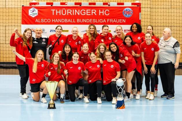 28.08.2025, GER, Handball, Frauen, Saison 2025 2026, Alsco 1.Bundesliga, Thueringer HC Saisoneröffnung öffentliches Training Mannschaftspraesentation zeigt die Mannschaft des Thueringer HC mit den beiden Pokalen des EHF European Cup und dem DHB-Super Cup, Julie Holm (Thueringer HC,8) Herbert Mueller (Thueringer HC,Trainer) Josefine Hanfland (Thueringer HC,57) Johanna Reichert (Thueringer HC,29) Anika Niederwieser (Thueringer HC,14) Kim Ott (Thueringer HC,25) Laura Kuske (Thueringer HC,11) Sharon Nooitmeer (Thueringer HC,3) Csenge Kuczora (Thueringer HC,59) Helfried Mueller (Thueringer HC,Co-Trainer) Rikke Hoffbeck Petersen (Thueringer HC,22) Natsuki Aizawa (Thueringer HC,23) Nathalie Hendrikse (Thueringer HC,6) Christina Loevgren Hallberg (Thueringer HC,1) Giulia Guarieiro (Thueringer HC,13) Jana Scheib (Thueringer HC,20) Maria Galic (Thueringer HC, Sportsphysiotherapeutin) Anna Szabo (Thueringer HC,26) Dilayla Alarslan (Thueringer HC,38) Luca Farago (Thueringer HC,19) 99947 Bad Langensalza Salza Halle Sporthalle Mehrz Thüringen Deutschland
