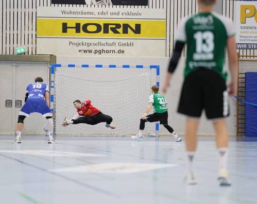 Deutschland - Kelkheim - Münster - 30.08.2025 Handball - Hessen - 3. Liga - Staffel Süd-West - Herren Saison 2025 2026 (2. Spieltag) TSG Münster (blau) - HG Saarlouis (grün) v.l. Torwart Fin Welkenbach (TSG Münster - 23), Elyas Noh (HG Saarlouis - 33) TSG Münster - HG Saarlouis