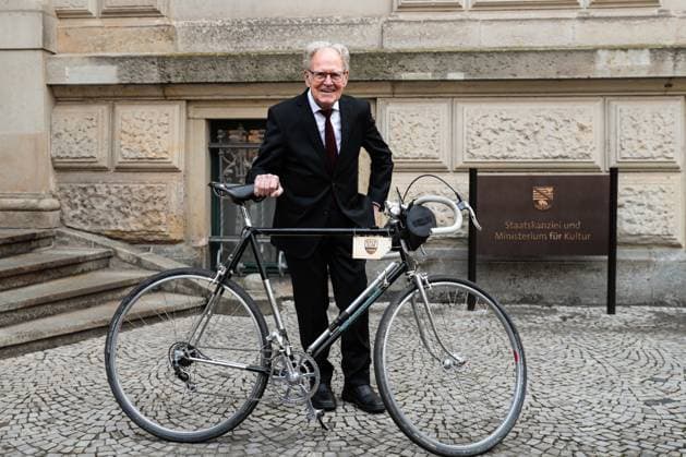 Gustav-Adolf Täve Schur steht mit einem Rennrad vor der Staatskanzlei. Gustav-Adolf Täve Schur, der 94-jährige frühere Radsportler wird für seine Verdienste um den für sein motivierendes Engagement zur Förderung des Nachwuchses und für seine bis heute bestehende Vorbildwirkung geehrt. Er gewann unter anderem 1955 und 1959 die Internationale Friedensfahrt sowie 1958 und 1959 die Straßenweltmeisterschaft der Amateure. Bis heute ist er ein beharrlicher Motivator für Bewegung, gesunde Ernährung und Gemeinsinn. Ministerpräsident Dr. Reiner Haseloff (CDU, Sachsen-Anhalt) hat am Mittwoch, 17. September 2025, in der Magdeburger Staatskanzlei den Verdienstorden des Landes Sachsen-Anhalt an eine Bürgerin und sechs Bürger überreichen.