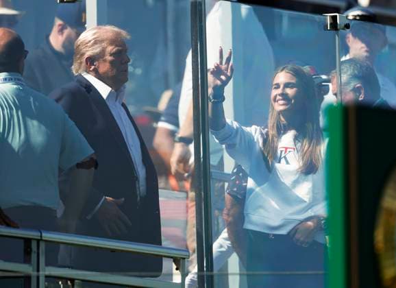 President Donald Trump s granddaughter Kai Trump (R) waves to the crowd from behind a bulletproof glass wall as she and the president attend the opening day of the 45th Ryder Cup at The Black Course at Bethpage State Park in Farmingdale, New York on Friday, September 26, 2025.  RYD20250926818 JOHNxANGELILLO