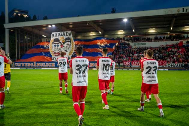 Die Spieler klatschen den Fans vor dem Spiel zu. Im Hintergrund ist die Choreo der Fans von Siegen zu sehen Sportfreunde Siegen - VfL Bochum U21, U 21 26.09.2025 Fussball, Regionalliga West, 10. Spieltag, GER, Siegen, Leimbachstadion Siegen Copyright: HMBxMedia xMarcoxBader