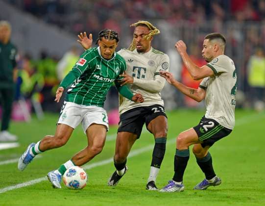 26.09.2025, Fussball Bundesliga 2025 2026, 5.Spieltag, FC Bayern München - SV Werder Bremen, in der Allianz-Arena München, v.l. Isaac Schmidt (Werder Bremen) gegen Sacha Boey (FC Bayern München) und Raphael Guerreiro (FC Bayern München)