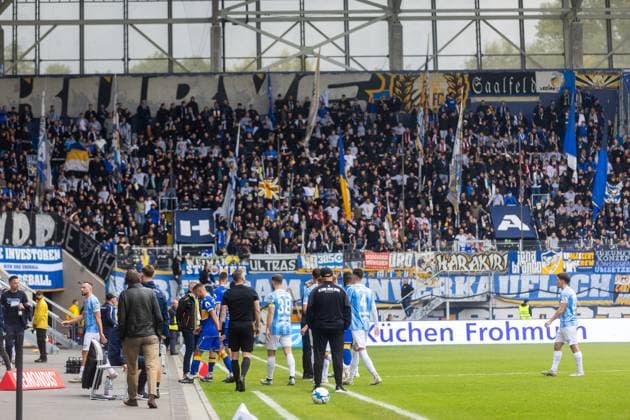 Jena , 270925, Fussball Regionalliga , FC Carl Zeiss Jena gegen Chemnitzer FC im Bild: Fans Ultras Jena Horda provozieren Spielunterbrechung indem sie zwei Fluchttore mit Transparenten und Fanen im Block versprerren Mannschaften verlassen das Feld