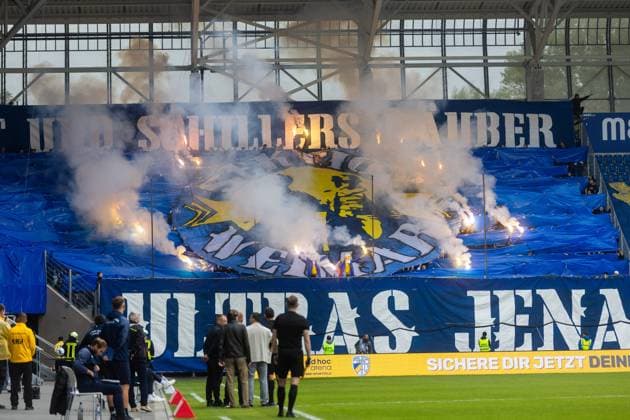 Jena , 270925, Fussball Regionalliga , FC Carl Zeiss Jena gegen Chemnitzer FC im Bild: Fans Ultras Jena Horda provozieren Spielunterbrechung indem sie zwei Fluchttore mit Transparenten und Fanen im Block versprerren