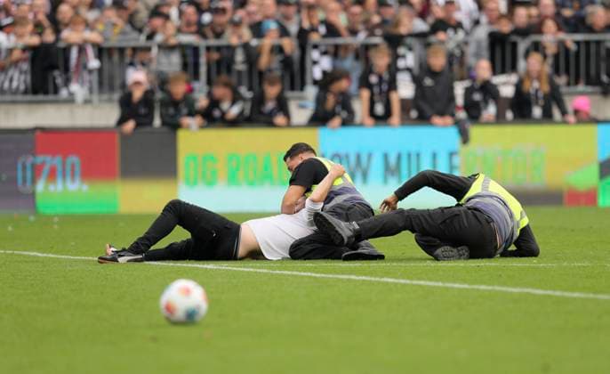 Foto : immer wieder die berühmte Nummer : ein Flitzer aus dem Publikum stürmt das Spielfeld und wird von 3 Sicherheitskräften Ordnern) überwältigt Fussball 1. Bundesliga , 5. Spieltag am Sa. 27.09.2025 FC St. Pauli - Bayer 04 Leverkusen 1 - 2