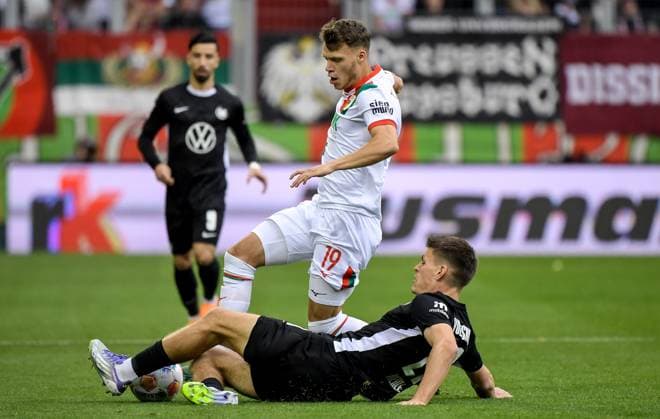 04.10.2025, xemx, Fussball 1.Bundesliga, FC Augsburg - VfL Wolfsburg v.l. Robin Fellhauer (FC Augsburg), Joakim Maehle (VfL Wolfsburg) Zweikampf, Aktion, action, battle for the ball (DFL DFB REGULATIONS PROHIBIT ANY USE OF PHOTOGRAPHS as IMAGE SEQUENCES and or QUASI-VIDEO) Augsburg