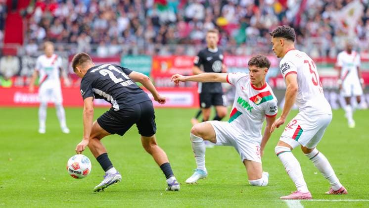 Mert Kömür (36, FC Augsburg), spielt den Ball im knien, Joakim Maehle (21, VfL Wolfsburg) und Fabian Rieder (32, FC Augsburg) beim Spiel zwischen FC Augsburg v VfL Wolfsburg, Fußball, Herren, Bundesliga, 2025 2026, 6.Spieltag am 04.10.2025 in Augsburg, WWK-Arena. DFL and DFB regulations prohibit any use of photographs as image sequences and or quasi-video. Bayern Deutschland