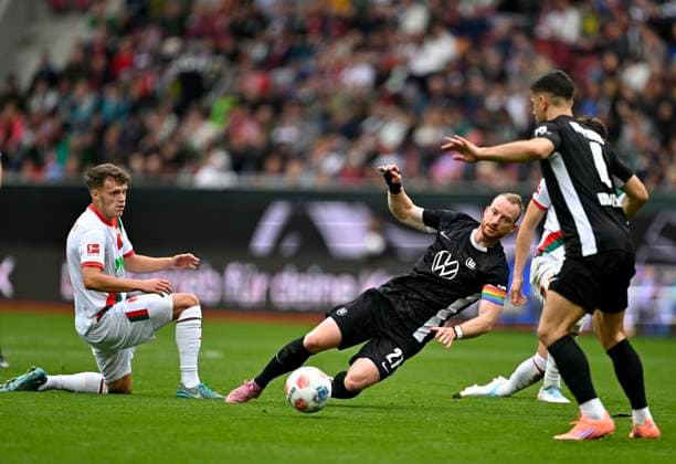 04.10.2025, Fussball 1. Bundesliga 2025 2026, 6.Spieltag, FC Augsburg - VfL Wolfsburg, in der WWK-Arena Augsburg. Maximilian Arnold (Wolfsburg) kommt zu Fall.
