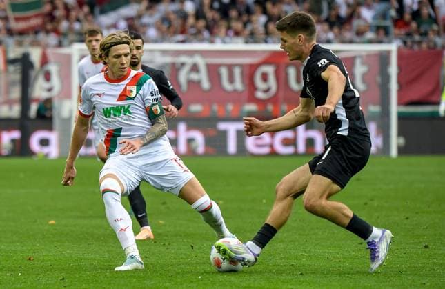 04.10.2025, xemx, Fussball 1.Bundesliga, FC Augsburg - VfL Wolfsburg v.l. Robin Fellhauer (FC Augsburg), Joakim Maehle (VfL Wolfsburg) Zweikampf, Aktion, action, battle for the ball (DFL DFB REGULATIONS PROHIBIT ANY USE OF PHOTOGRAPHS as IMAGE SEQUENCES and or QUASI-VIDEO) Augsburg