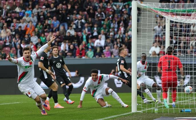 04.10.2025, 1. Bundesliga , FC Augsburg vs VfL Wolfsburg, WWK Arena Augsburg , Fussball, im Bild: 1:0, Elvis Rexhbecaj (FC Augsburg), Noahkai Banks (FC Augsburg) jubeln , Kamil Grabara (VfL Wolfsburg) geschlagen