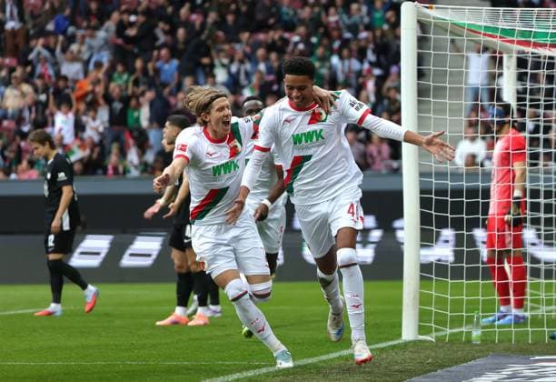 04.10.2025, 1. Bundesliga , FC Augsburg vs VfL Wolfsburg, WWK Arena Augsburg , Fussball, im Bild: 1:0, Kristijan Jakic (FC Augsburg), Noahkai Banks (FC Augsburg) jubeln , Kamil Grabara (VfL Wolfsburg) geschlagen