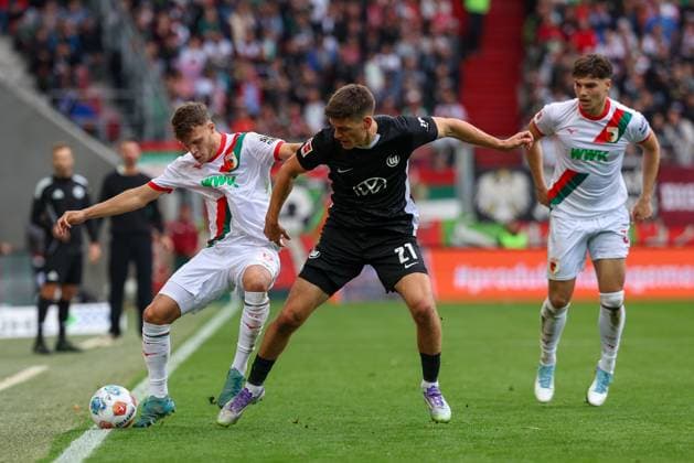 im Zweikampf, Aktion, mit Robin Fellhauer 19 (FC Augsburg), Joakim Maehle 21 (VfL Wolfsburg), Mert Koemuer 36 (FC Augsburg), FC Augsburg vs. VfL Wolfsburg, Fussball, 1. Bundesliga, 6. Spieltag, 04.10.2025 DFB regulations prohibit any use of photographs as image sequences and or quasi-video Augsburg Bayern Deutschland