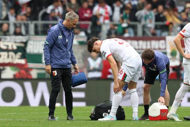 Mannschaftsarzt Dr. Karsten Bogner (FC Augsburg) unf Physiotherapeut, Nikolaus Guschl (FC Augsburg) schauen nach Mert Koemuer 36 (FC Augsburg), FC Augsburg vs. VfL Wolfsburg, Fussball, 1. Bundesliga, 6. Spieltag, 04.10.2025 DFB regulations prohibit any use of photographs as image sequences and or quasi-video Augsburg Bayern Deutschland