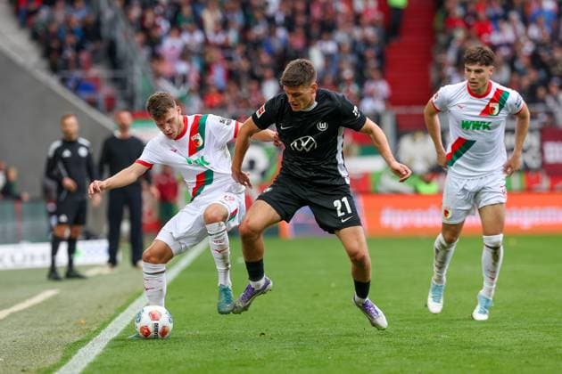 im Zweikampf, Aktion, mit Robin Fellhauer 19 (FC Augsburg), Joakim Maehle 21 (VfL Wolfsburg), Mert Koemuer 36 (FC Augsburg), FC Augsburg vs. VfL Wolfsburg, Fussball, 1. Bundesliga, 6. Spieltag, 04.10.2025 DFB regulations prohibit any use of photographs as image sequences and or quasi-video Augsburg Bayern Deutschland