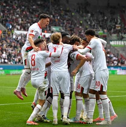 04.10.2025, Fussball 1. Bundesliga 2025 2026, 6.Spieltag, FC Augsburg - VfL Wolfsburg, in der WWK-Arena Augsburg. Mert Kömür (FC Augsburg) jubelt mit seinen Teamkollegen.
